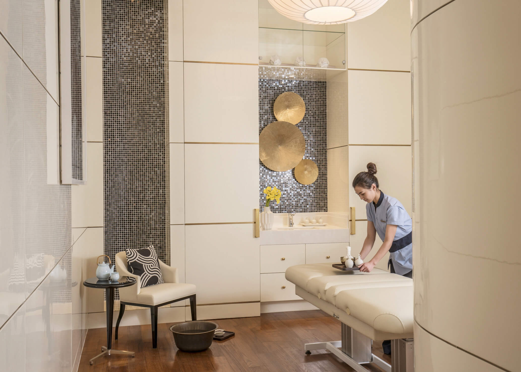 Therapist preparing a luxury treatment room with custom TouchAmerica millwork, vanity casework and wall panelling